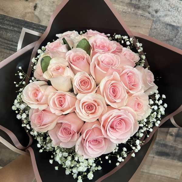 Bouquet of pale pink roses with baby's breath in black wrap