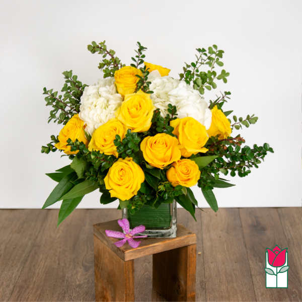 Yellow roses and white hydrangeas in a glass vase with greenery