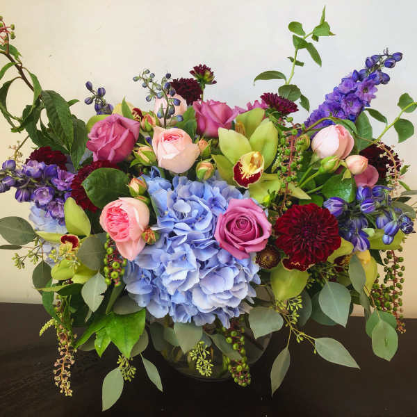 Mixed bouquet with pink roses, blue hydrangea, and purple flowers in a vase