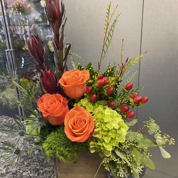 Orange roses and green hydrangea in a wooden box with berries