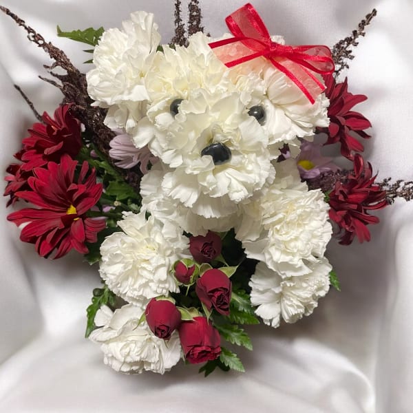 White teddy bear made of flowers with red blooms and a ribbon bow