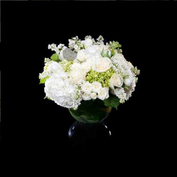 White roses and hydrangeas arranged in a glass vase