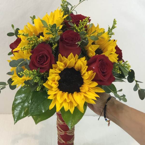Bouquet of red roses and yellow sunflowers with greenery