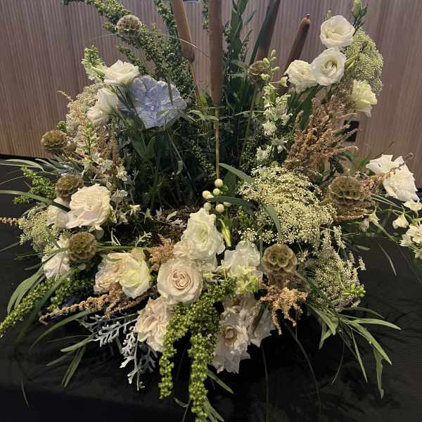 Large floral centerpiece with white roses and tall brown candles