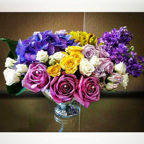 Colorful bouquet of roses, hydrangeas, and stock in a glass vase