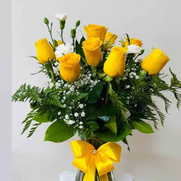Yellow roses in a glass vase with a yellow ribbon