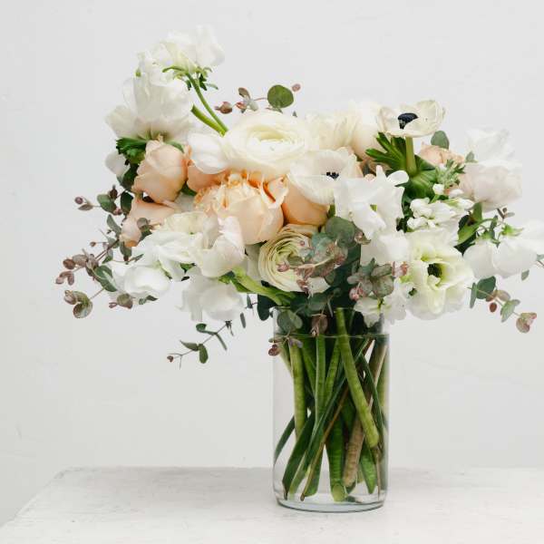 White and blush flowers arranged in a clear glass vase