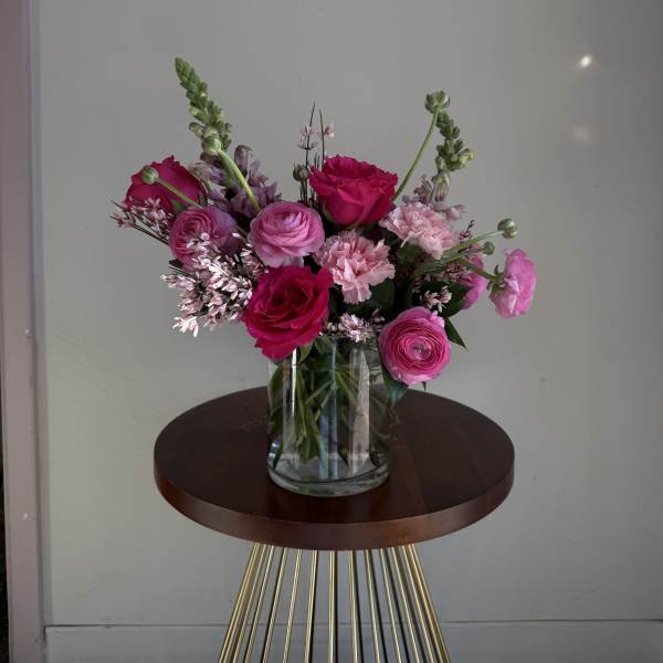 Pink and magenta flowers arranged in a clear glass vase