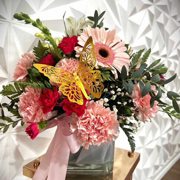 Pink and red mixed bouquet in a glass vase with a butterfly decoration