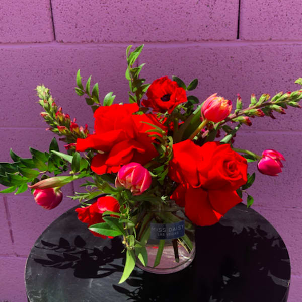 Red roses and pink tulips in a clear glass vase