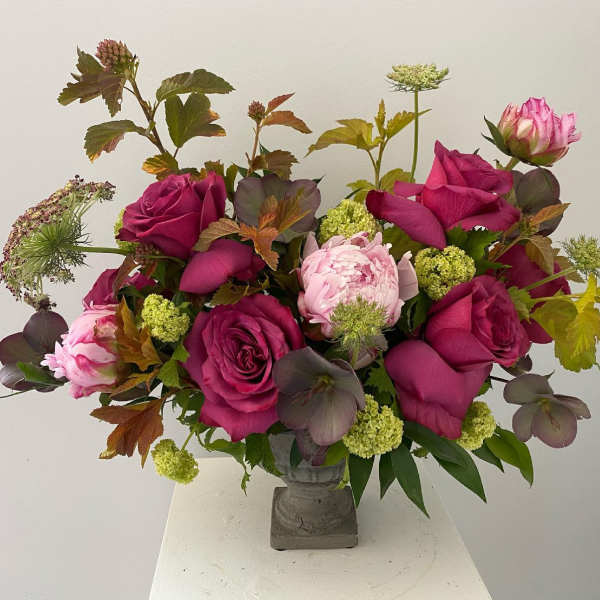 Bouquet of magenta roses and pink peonies in a gray vase
