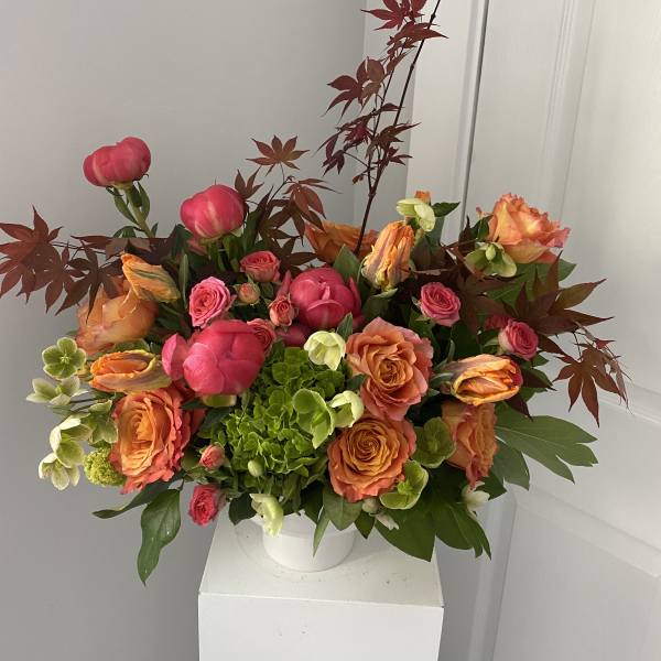 Bouquet of pink and orange roses with green hydrangea in a white vase