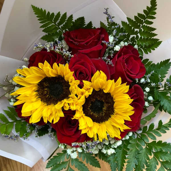 Bouquet of red roses and yellow sunflowers wrapped in white paper