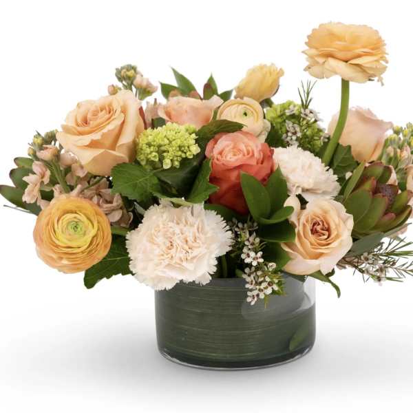 Peach and coral flower arrangement in a dark green vase