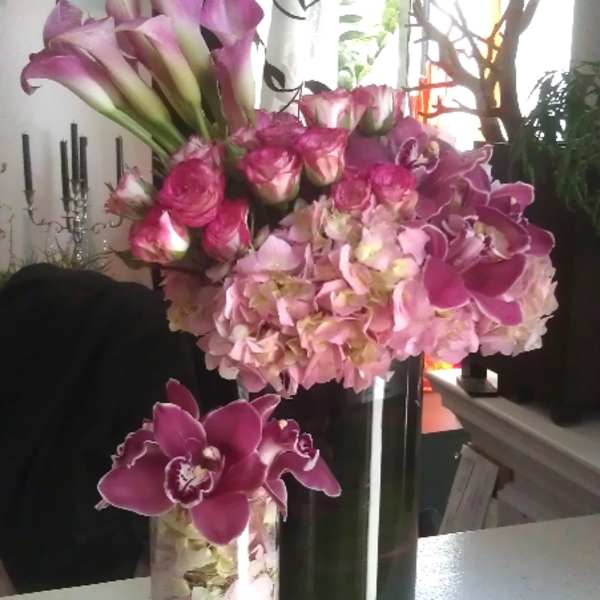 Pink calla lilies and orchids arranged in glass vases