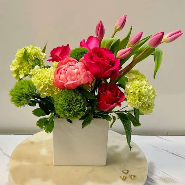 Pink tulips and roses in a white square vase