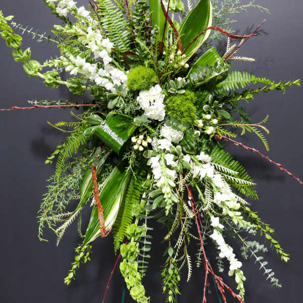 Tall floral spray with white blooms and lush green foliage