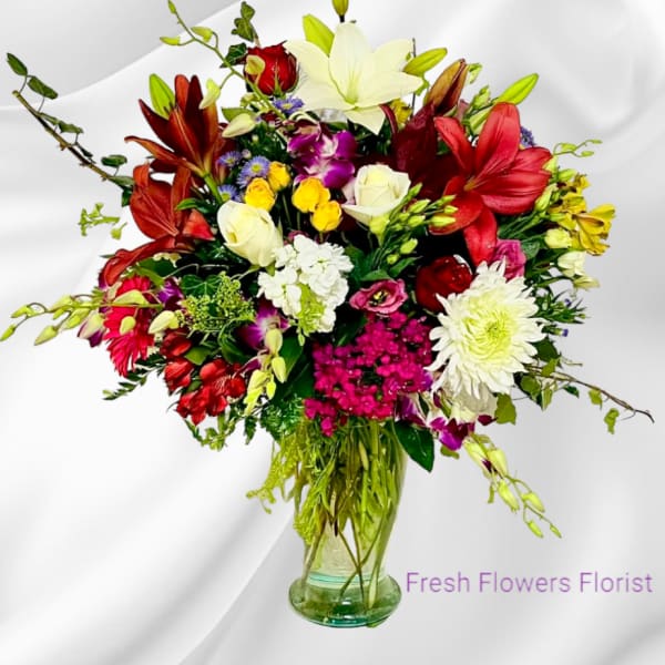 Mixed bouquet of lilies, roses, and daisies in a glass vase