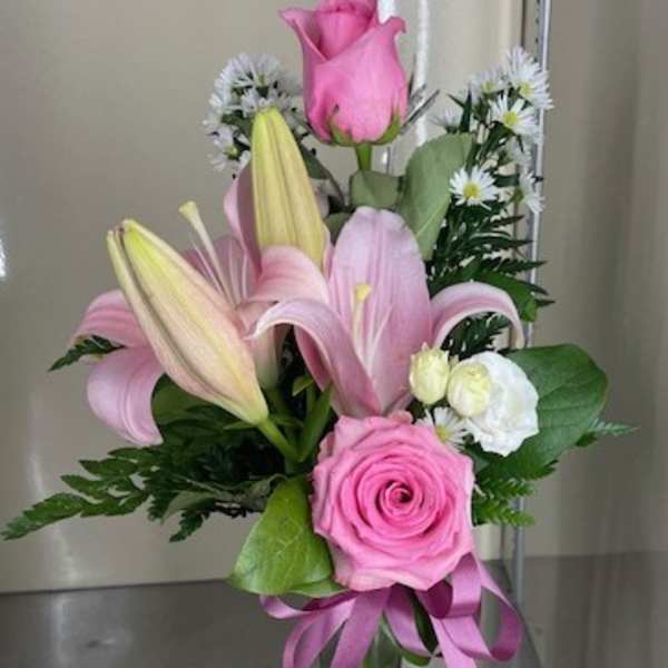 Pink roses and lilies arranged in a clear glass vase