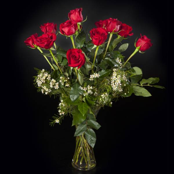 Red roses in a clear glass vase with small white filler flowers