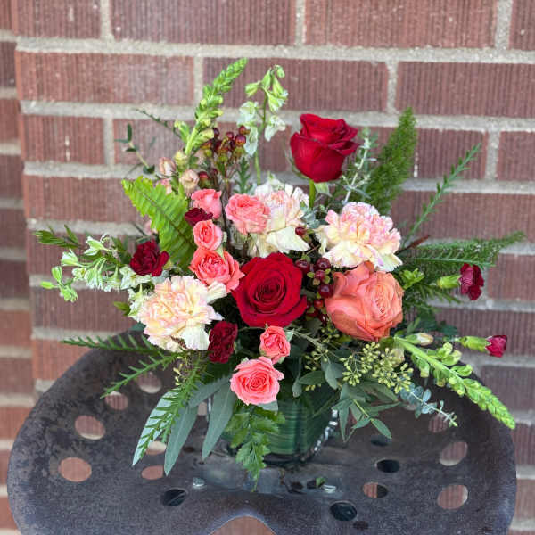 Mixed bouquet of red and pink roses with carnations in a glass vase