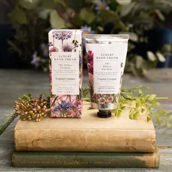 Two floral hand cream tubes and boxes on stacked books