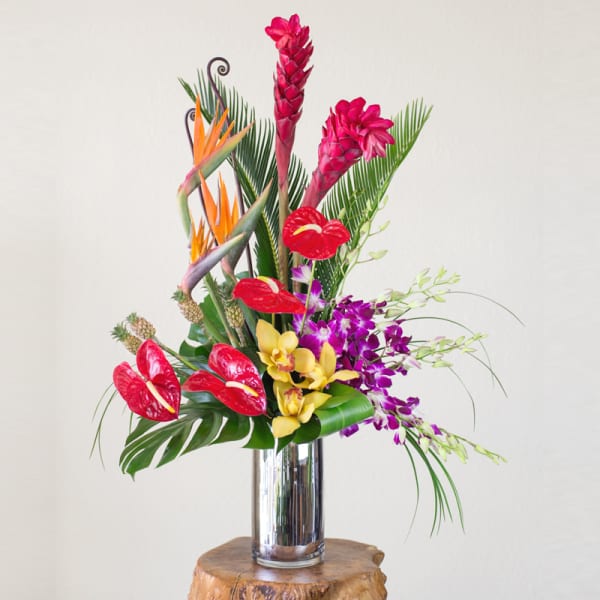 Tropical flower arrangement in a tall silver vase