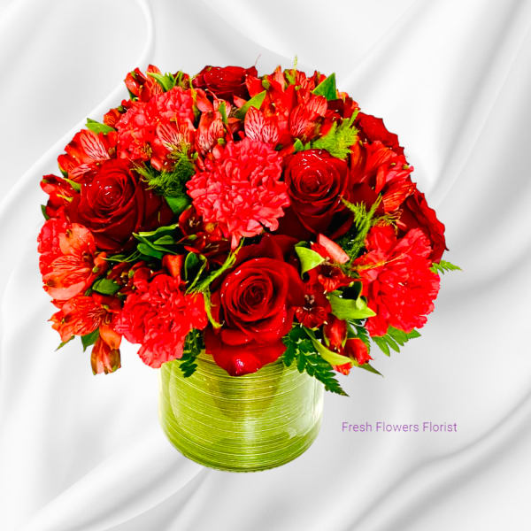 Red roses and mixed red flowers arranged in a green vase