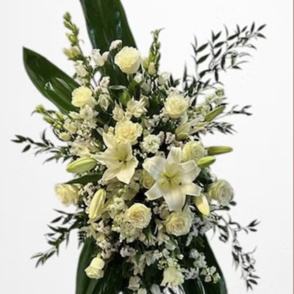White floral standing spray with lilies and roses on a metal easel