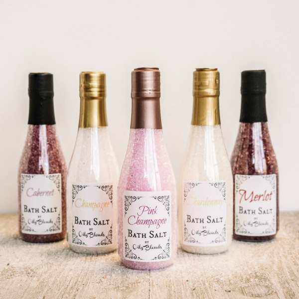 Five labeled bottles of bath salt in pink, gold, and white tones