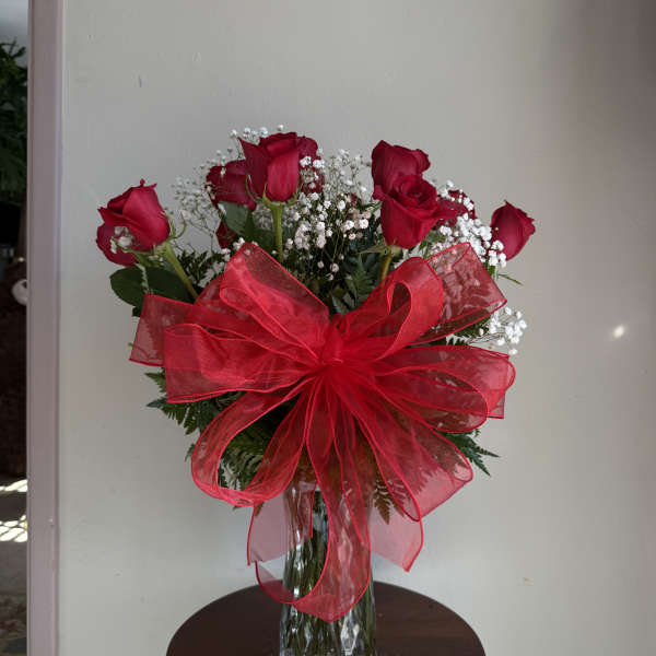 Red roses in a glass vase with a large red bow