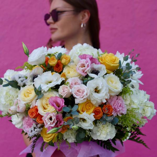 Large bouquet of mixed roses and white blooms in pink wrapping