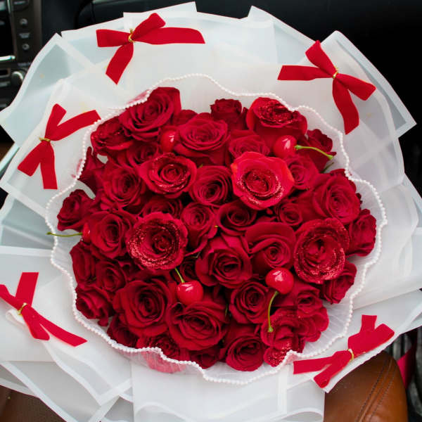 Bouquet of red roses wrapped in white paper with red bows