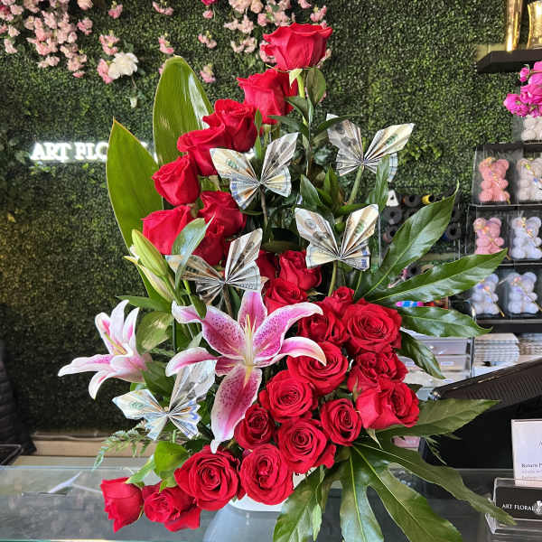 Red roses and pink lilies in a vase with folded money accents