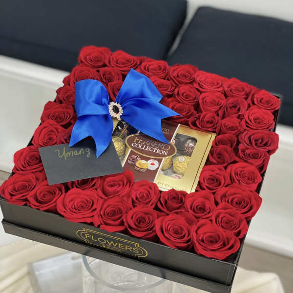 Box of red roses with a blue bow and chocolates