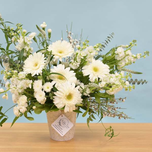 White gerbera daisies and mixed white flowers in a patterned vase