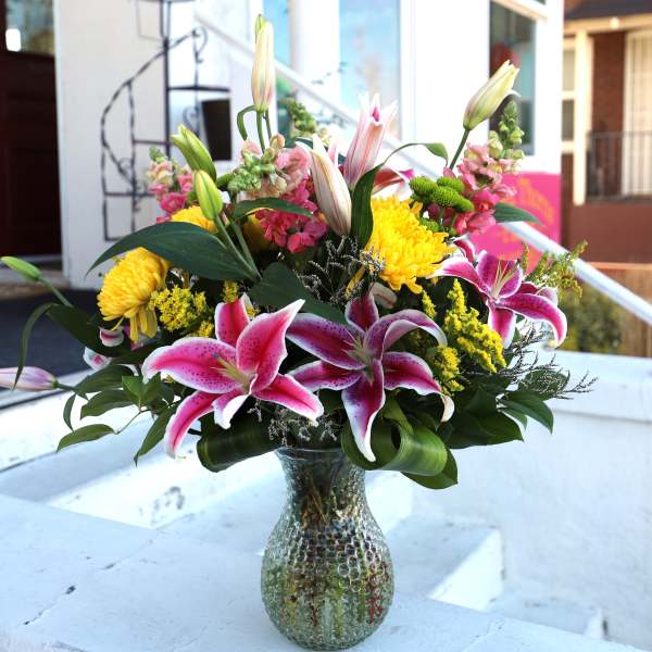 Pink lilies and yellow chrysanthemums in a glass vase