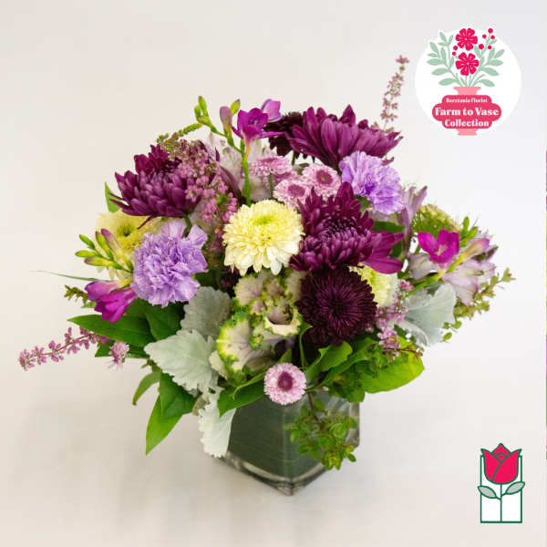 Mixed purple and white bouquet in a square glass vase