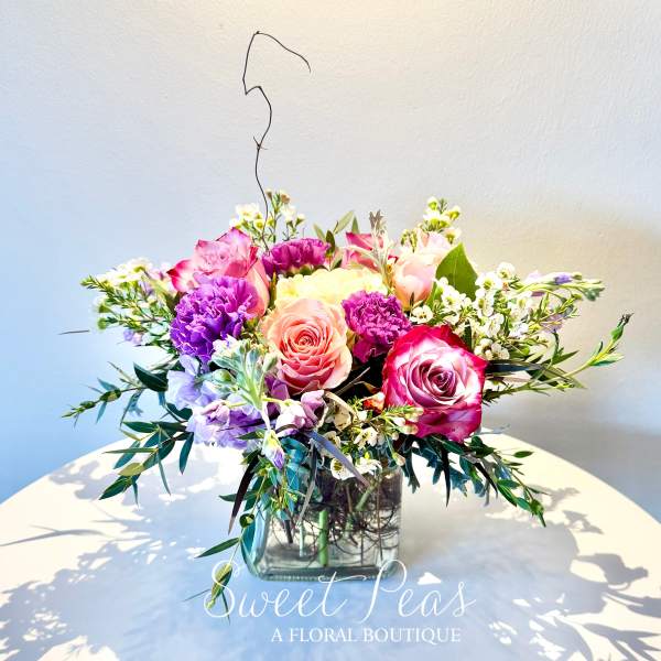 Mixed pink and purple bouquet in a square glass vase