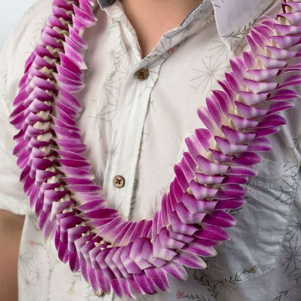Purple and white orchid petal lei draped around a person’s neck