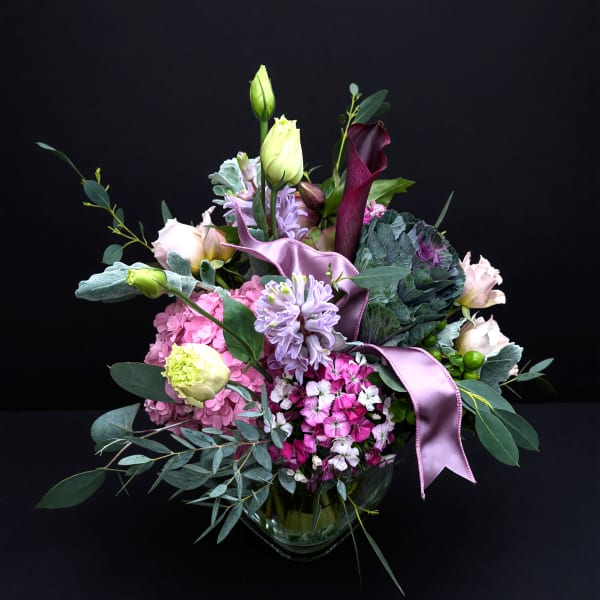 Mixed bouquet with pink, lavender, and white flowers in a glass vase