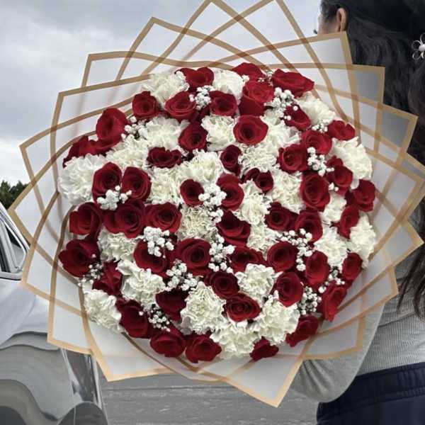 Large bouquet of red roses and white carnations wrapped in tan paper
