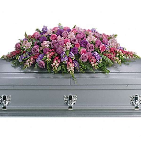 Large pink and purple floral casket spray on a gray casket