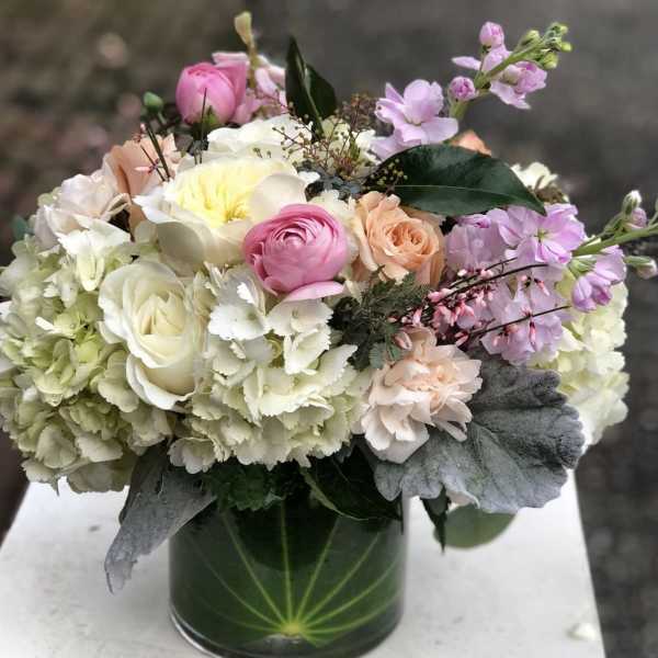 Pastel bouquet of roses, hydrangeas, and ranunculus in a glass vase