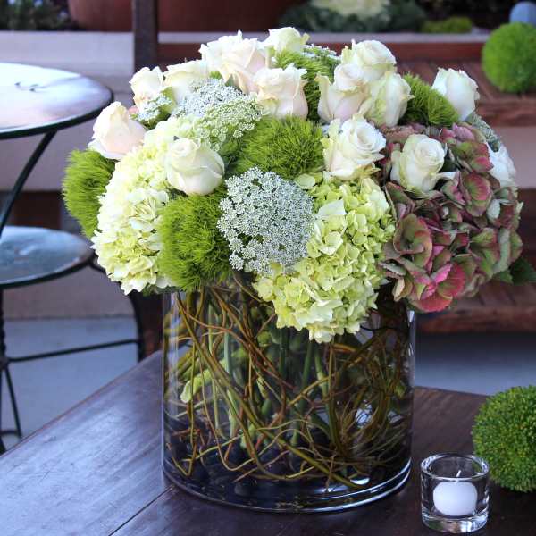 White roses and green hydrangeas in a glass vase