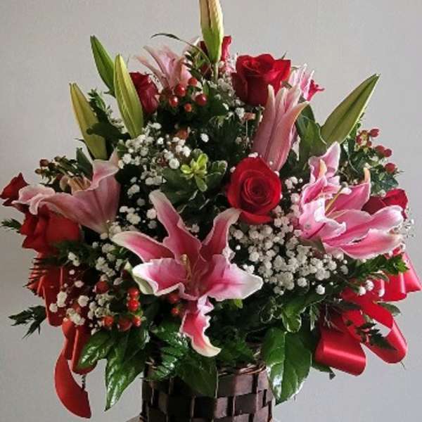 Basket arrangement of pink lilies and red roses with baby's breath