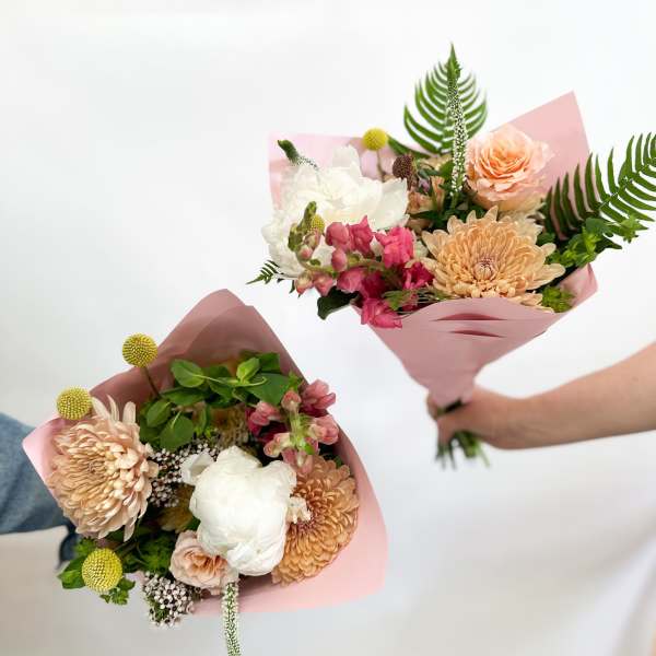 Two hand-held bouquets with peach, white, and pink flowers