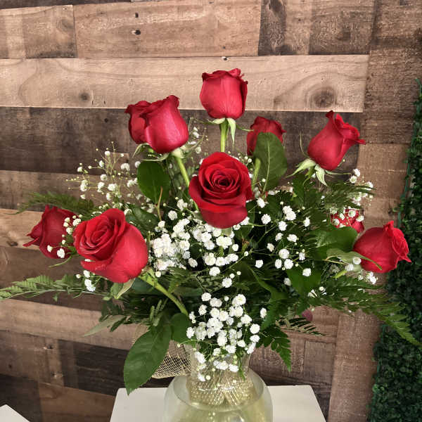 Red roses arranged in a clear glass vase with white baby's breath