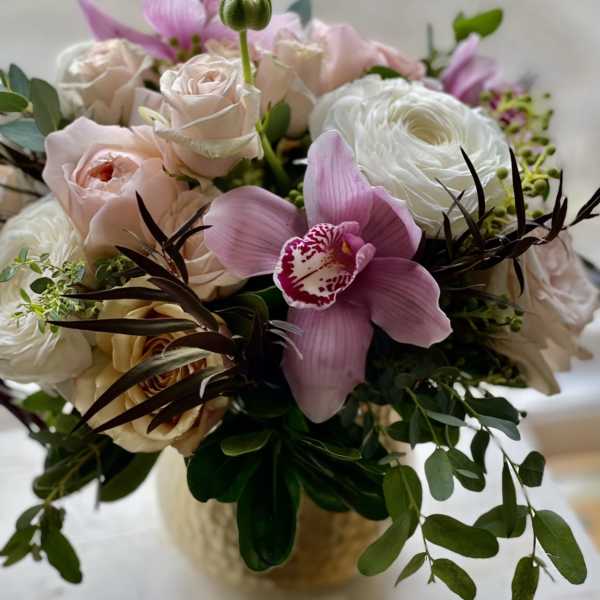 Pink and white floral bouquet with roses and orchids in a vase