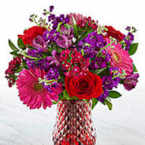 Mixed bouquet of red, pink, and purple flowers in a glass vase